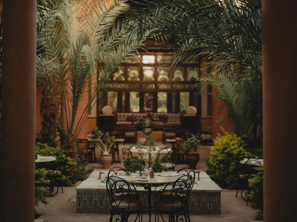 Patio restaurante de Al Moudira Hotel entre palmeras y fuentes