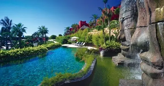 Piscina Caras de Angkor de Asia Gardens con esculturas de piedra y vegetación tropical